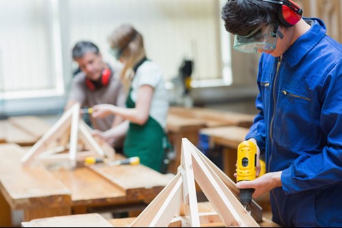 Young person using a drill in a wood working class