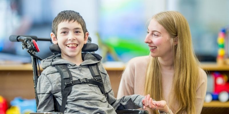 Young boy in wheelchair with support assistant