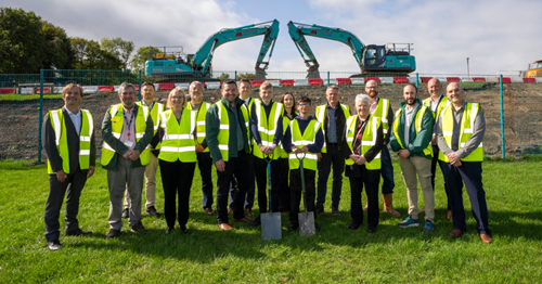 Group of people in hi viz jackets holding spades